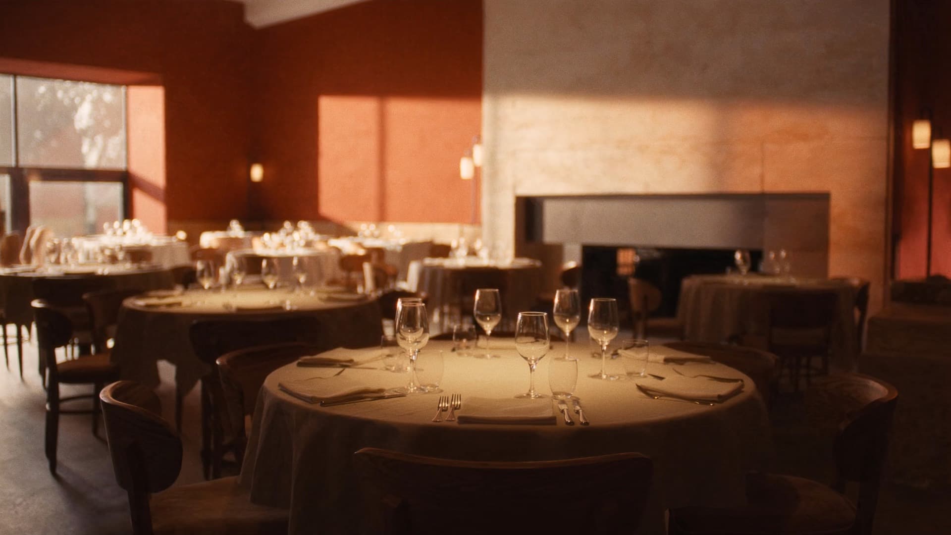 Sala de un restaurante contemporáneo al atardecer, con las mesas puestas y luz cálida entrando por el ventanal